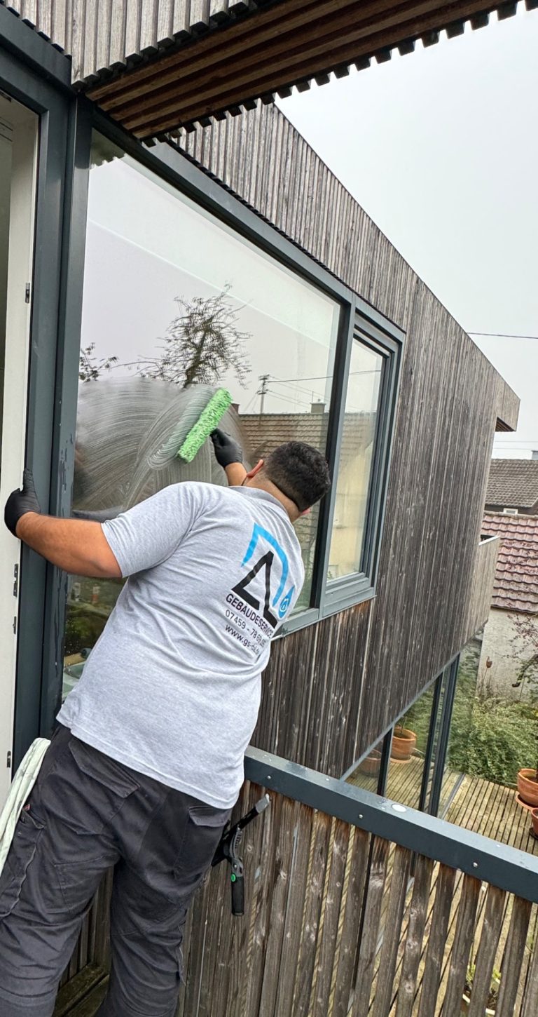 Professionelle Fensterreinigung Nagold Professioneller Fensterputzer von Gebäudeservice Dal reinigt ein großes Fenster an einer modernen Fassade in Nagold.
